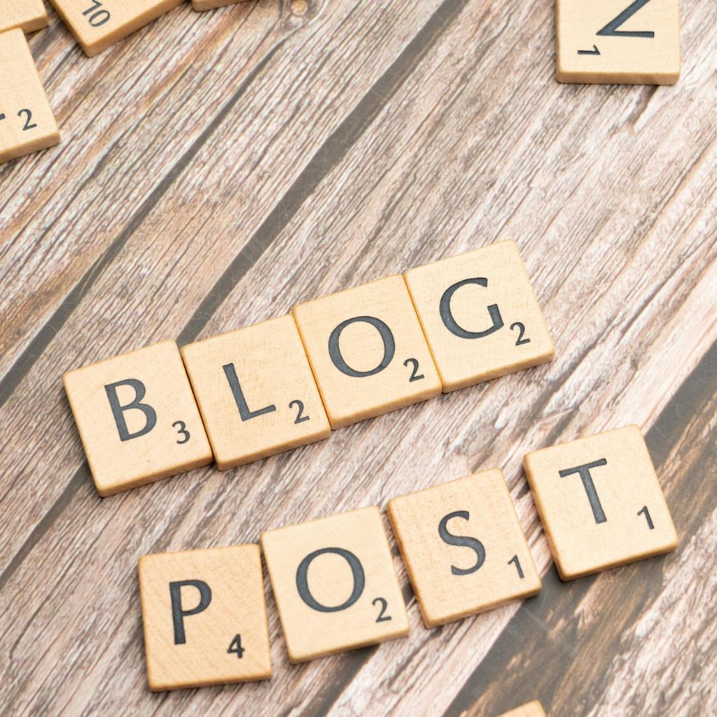 Scrabble tiles spelling out the words "BLOG POST" arranged on a wooden background.