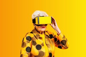 An older woman with white hair wearing a yellow and black polka-dot jacket and a yellow VR headset against a solid yellow background.