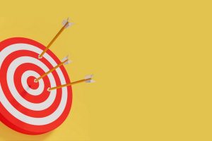 A red and white bulls-eye target on a solid yellow background, with three arrows stuck in it, one hitting the center.