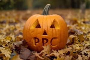 Carved Halloween pumpkin resting on autumn leaves with the letters 'PPC' carved into the front.