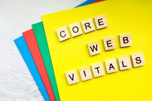 Wooden tiles spelling out "CORE WEB VITALS" on a yellow background with colourful paper edges.