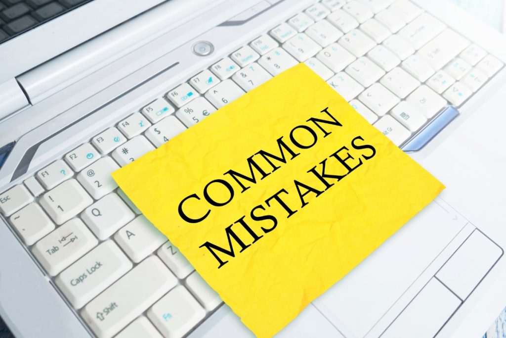 A yellow sticky note with the words "COMMON MISTAKES" placed on a white laptop keyboard.