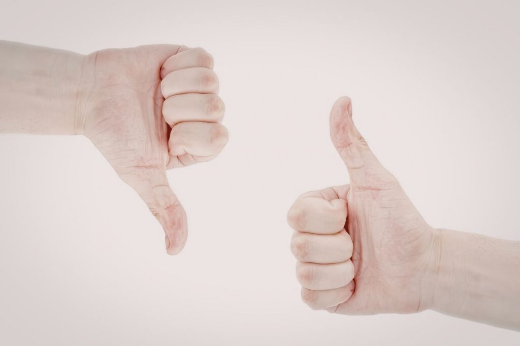 A side-by-side comparison of two hands: one showing a "thumbs down" gesture and the other showing a "thumbs up" gesture.