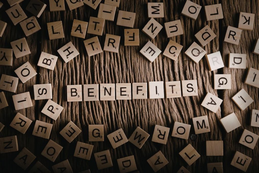 A group of professionals in business attire standing together in a bright, modern office, smiling and looking toward the camera.