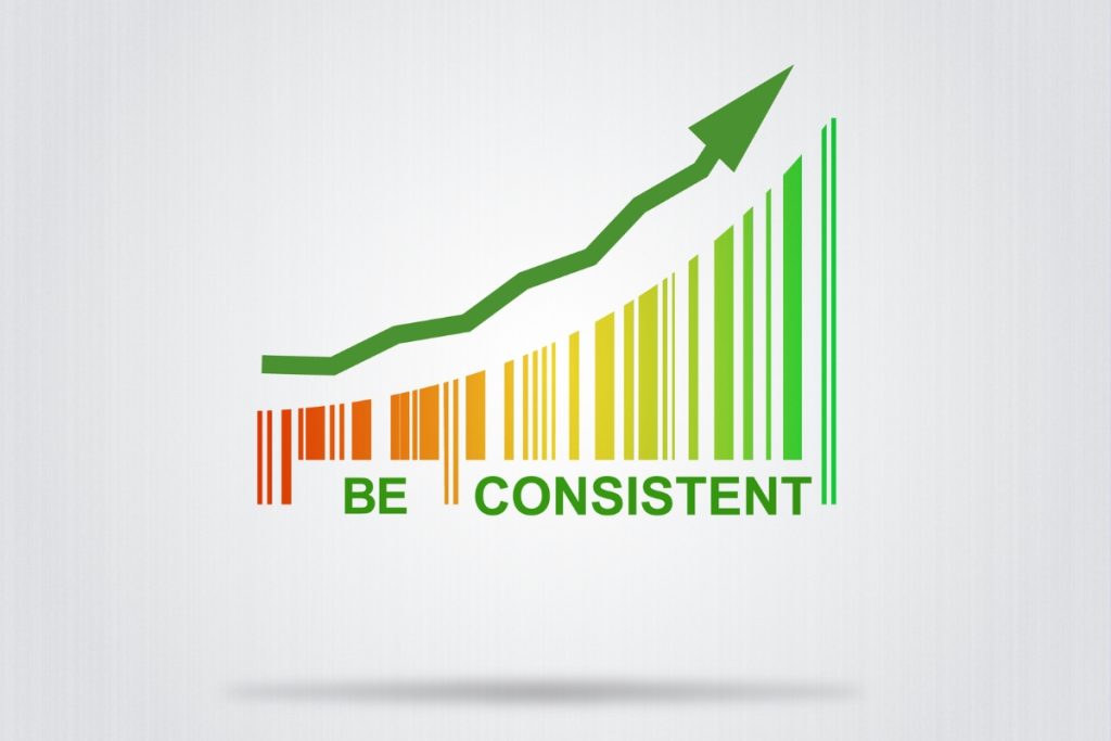A graphic illustration of a rising green arrow moving upwards over a multicolored bar chart resembling a barcode, with the text "BE CONSISTENT" written underneath.