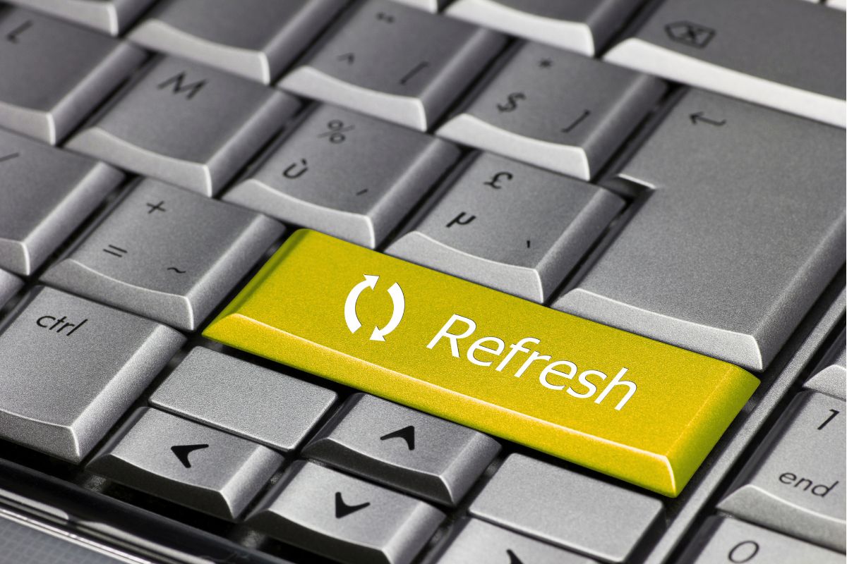A close-up view of a computer keyboard featuring a bright yellow key with a refresh icon and the word "Refresh."