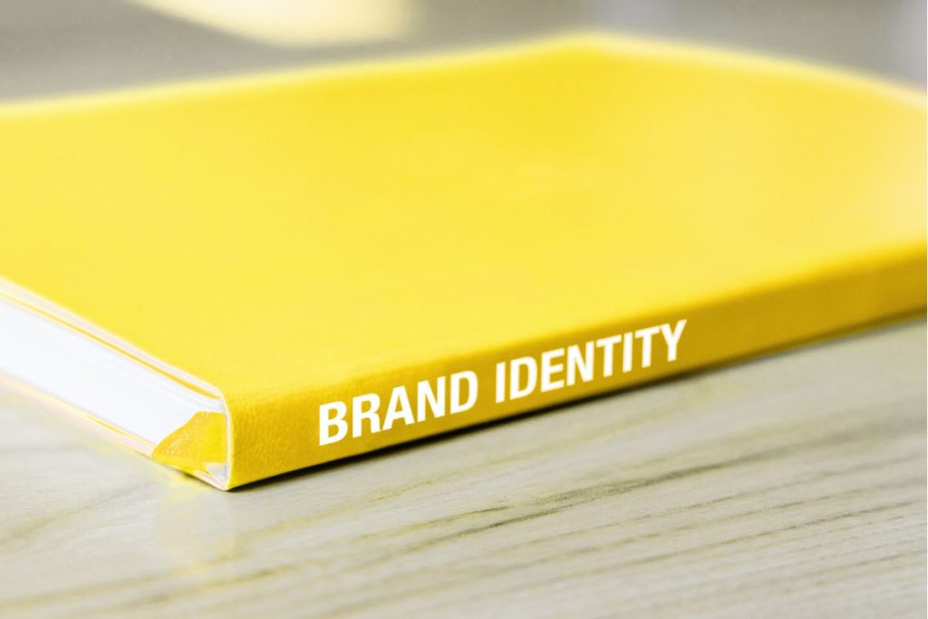 A close-up of a vibrant yellow hardcover notebook with the words "BRAND IDENTITY" printed on the spine.